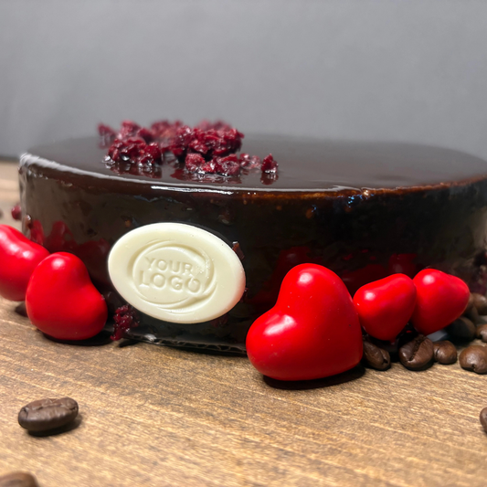 White chocolate decoration with a custom embossed oval logo on a chocolate cake