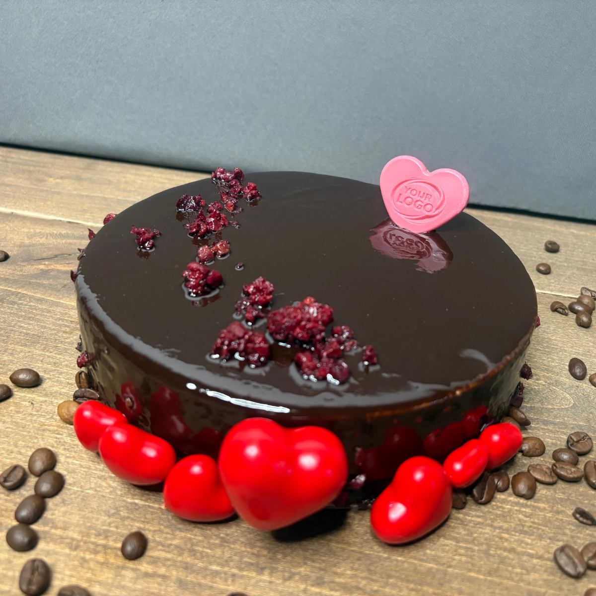 Pink heart-shaped chocolate with a custom logo used as a cake decoration
