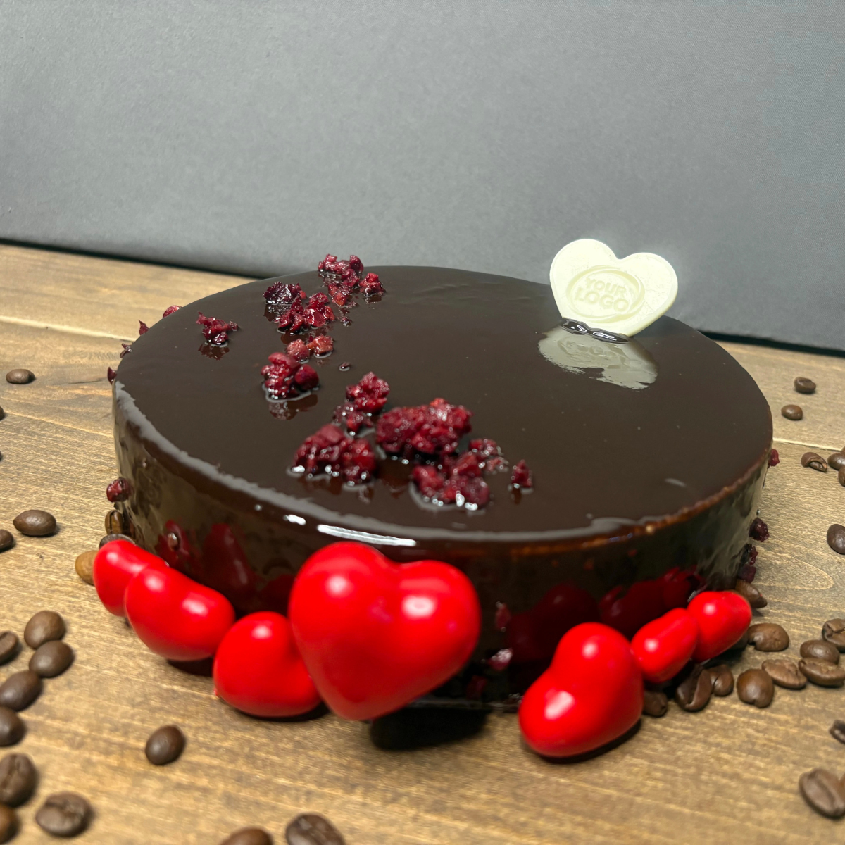White heart-shaped chocolate with a custom logo used as a cake decoration